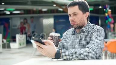 一个神情专注的男人在手机上打短信，手里拿着咖啡。